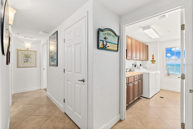 hallway featuring a textured ceiling, separate washer and dryer, and light tile patterned floors