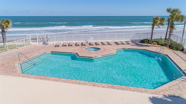 view of pool featuring a hot tub, a patio area, and a water view