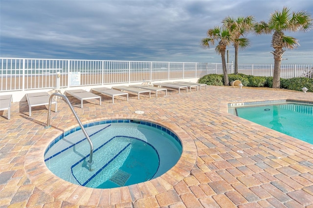 view of pool featuring a hot tub, a patio, and a water view