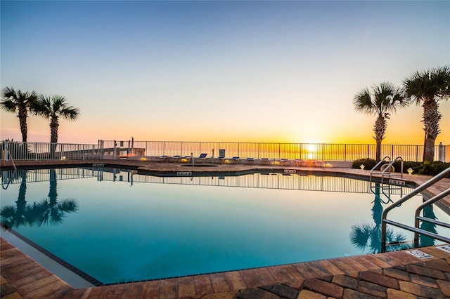 pool at dusk with a patio and a water view