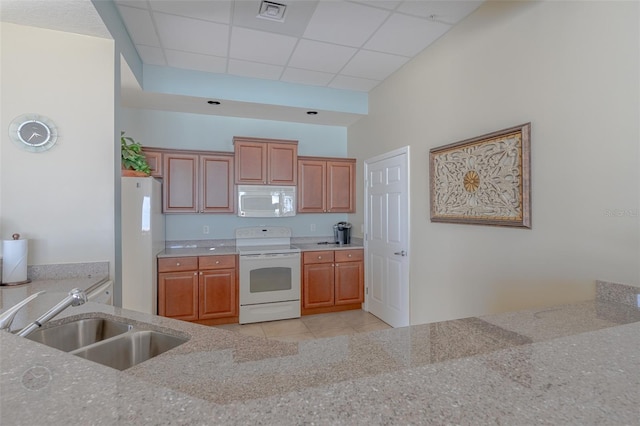 kitchen with a drop ceiling, white appliances, sink, and light tile patterned floors