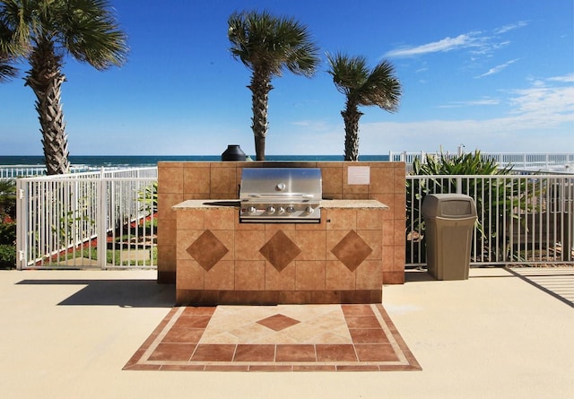 view of patio / terrace featuring a grill, area for grilling, a beach view, and a water view