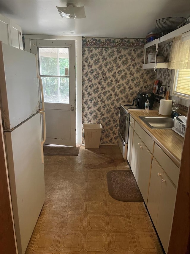 kitchen with sink, white cabinets, stainless steel electric range, and white refrigerator