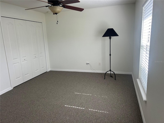 unfurnished bedroom featuring ceiling fan, a closet, a textured ceiling, and dark colored carpet