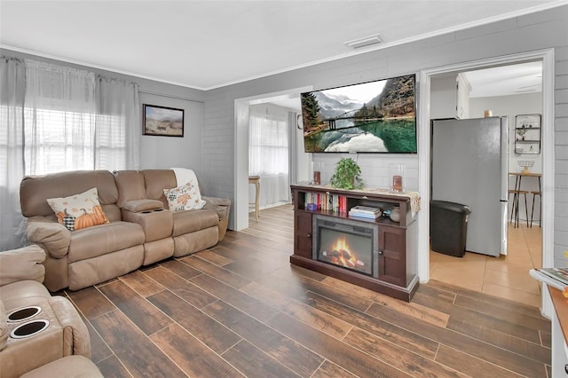 living room with crown molding, dark wood-type flooring, and a wealth of natural light