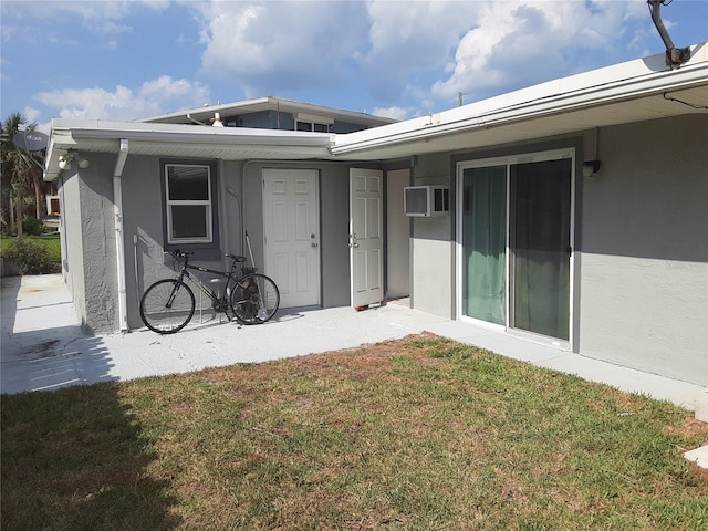 back of property featuring a wall unit AC and a lawn