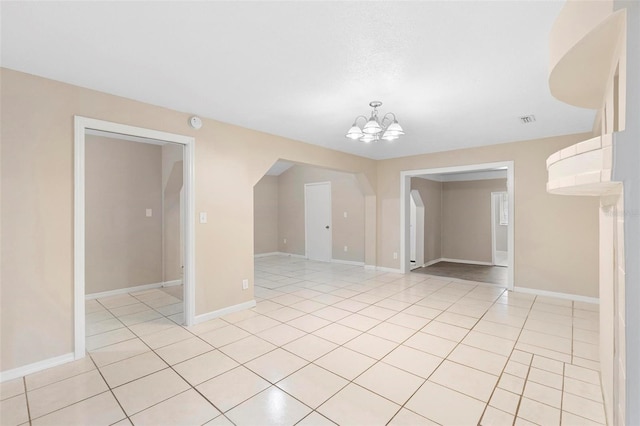 tiled spare room featuring a chandelier