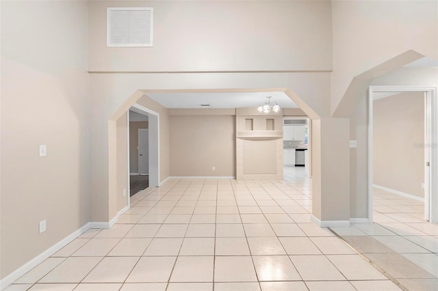 interior space with light tile patterned floors, a chandelier, and a high ceiling