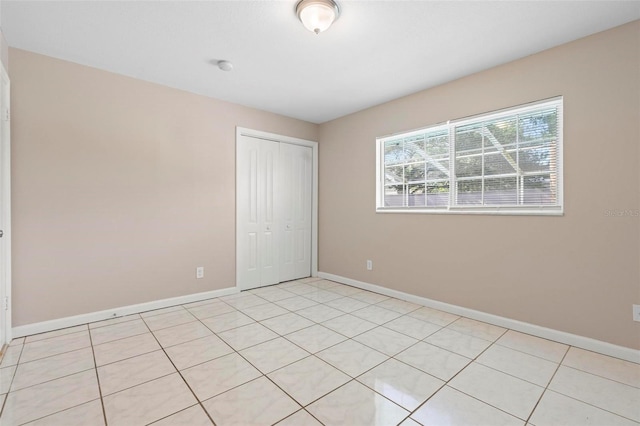 unfurnished bedroom with light tile patterned floors and a closet