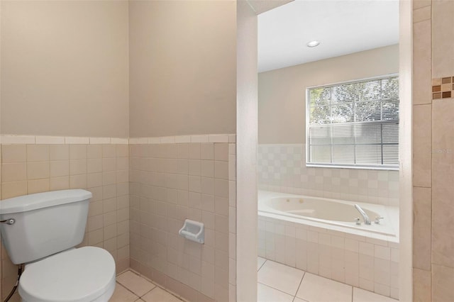 bathroom featuring tile patterned floors, a relaxing tiled tub, tile walls, and toilet