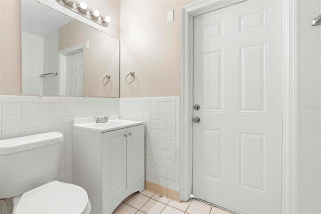 bathroom featuring tile patterned flooring, vanity, toilet, and tile walls