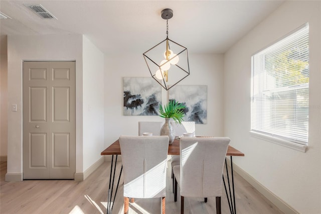 dining area featuring light wood-type flooring and an inviting chandelier