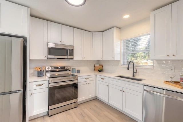 kitchen featuring decorative backsplash, sink, white cabinets, and stainless steel appliances