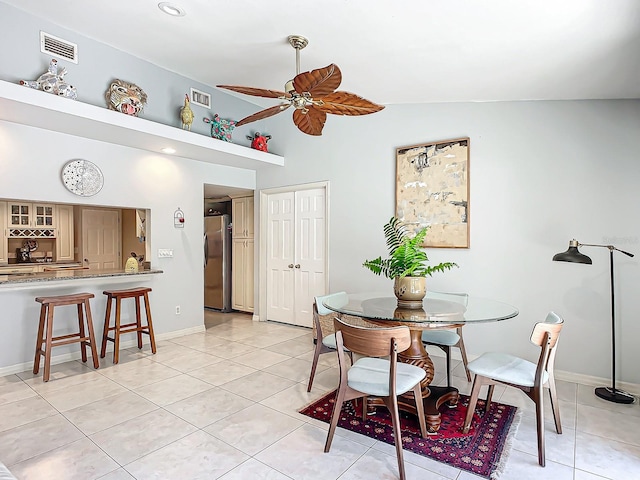 tiled dining area with ceiling fan and vaulted ceiling