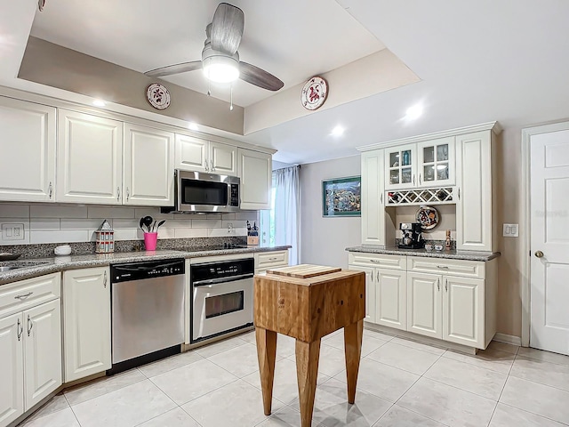 kitchen featuring white cabinets, backsplash, ceiling fan, and stainless steel appliances