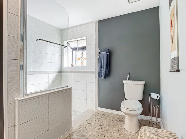 bathroom featuring tiled shower and toilet