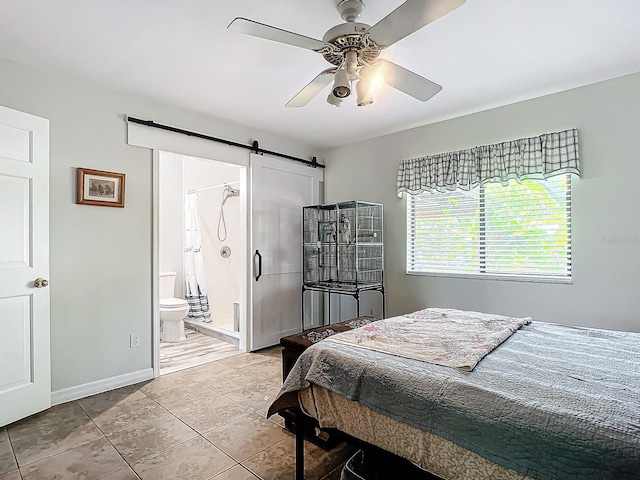 bedroom featuring connected bathroom, a barn door, ceiling fan, and tile patterned floors