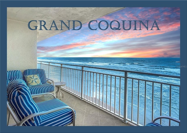 balcony at dusk with a water view and a beach view