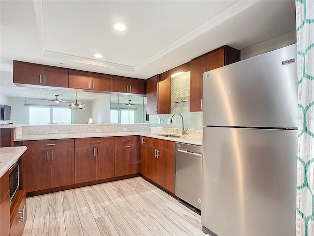 kitchen with stainless steel appliances, a raised ceiling, ceiling fan, sink, and decorative light fixtures