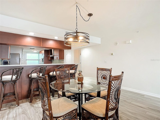 dining area with sink, light hardwood / wood-style flooring, and a notable chandelier