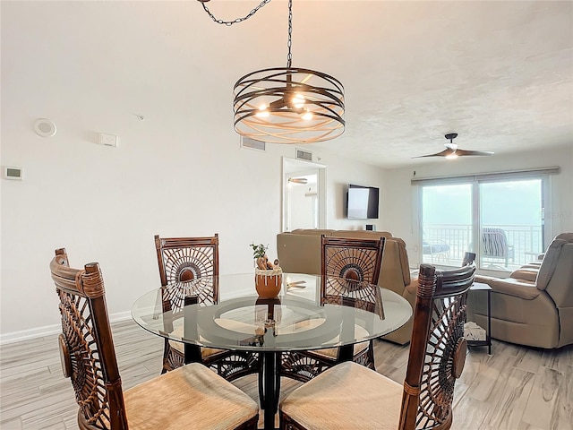 dining room featuring ceiling fan with notable chandelier and light hardwood / wood-style floors