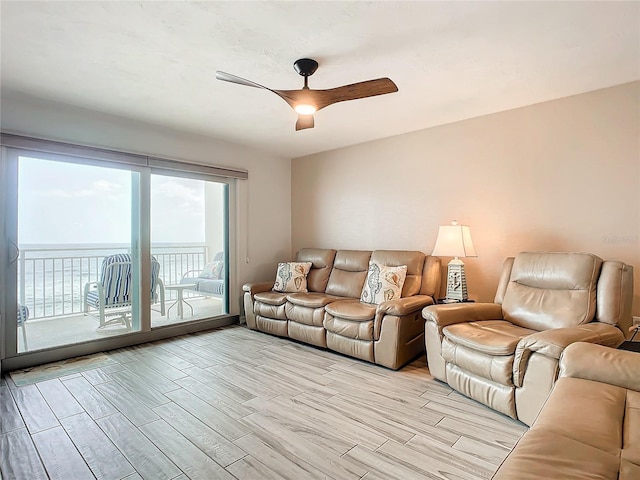 unfurnished living room with ceiling fan, a water view, and light wood-type flooring