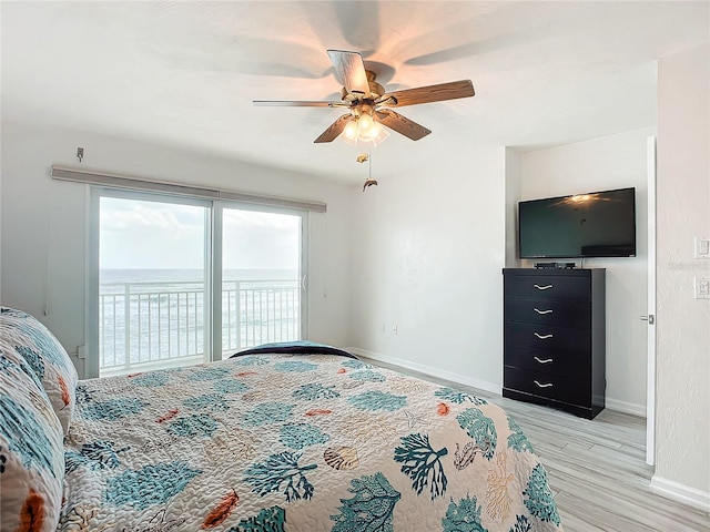 bedroom featuring access to exterior, ceiling fan, light hardwood / wood-style flooring, and a water view