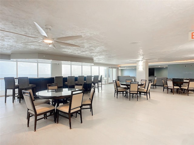 dining area featuring ceiling fan and a textured ceiling