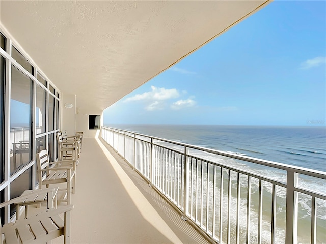 balcony with a water view and a view of the beach