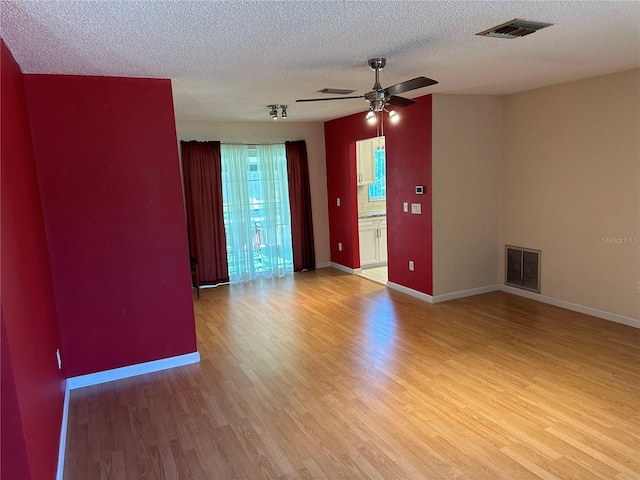 spare room with ceiling fan, a textured ceiling, and light hardwood / wood-style flooring