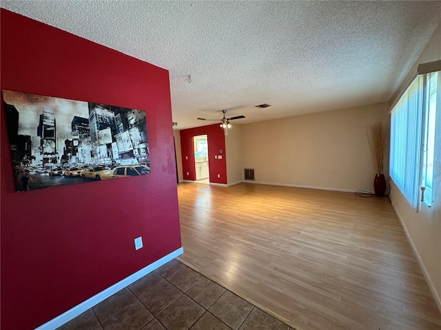 empty room with wood-type flooring, a textured ceiling, and ceiling fan