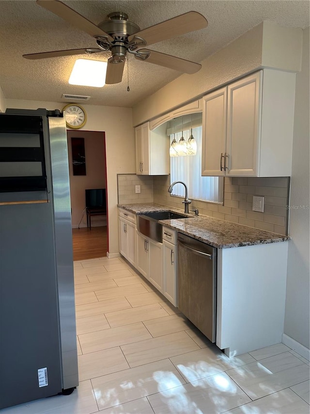 kitchen with white cabinets, sink, ceiling fan, a textured ceiling, and stainless steel appliances