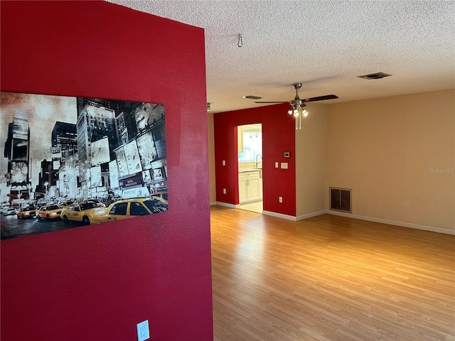 interior space with wood-type flooring, a textured ceiling, and ceiling fan