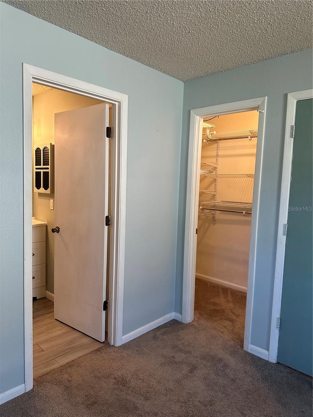 unfurnished bedroom featuring a spacious closet, a closet, carpet floors, and a textured ceiling