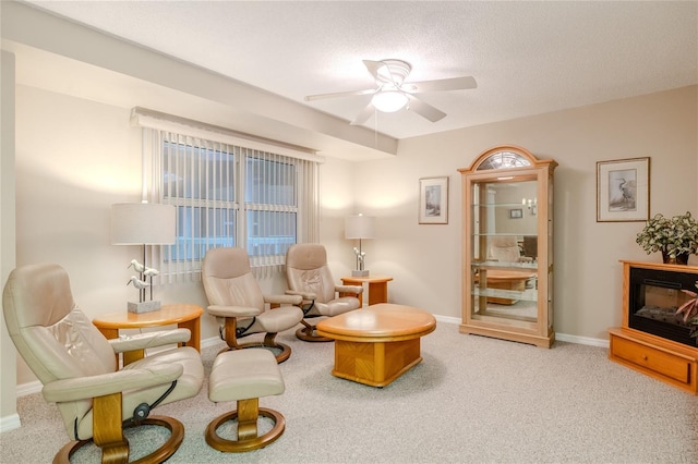 living area with carpet, a textured ceiling, and ceiling fan