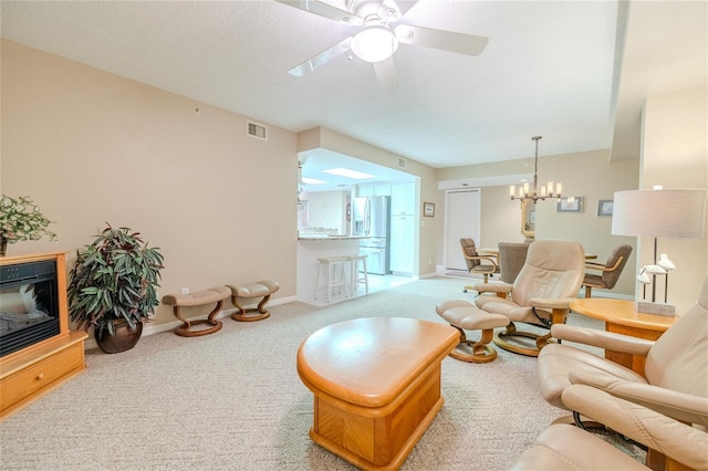 carpeted living room featuring ceiling fan with notable chandelier