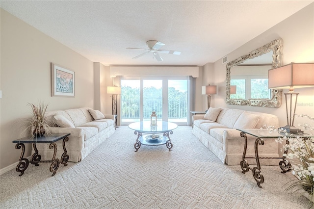 carpeted living room featuring ceiling fan and a textured ceiling