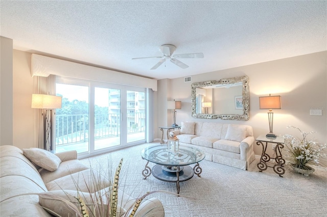 living room featuring carpet flooring, ceiling fan, and a textured ceiling