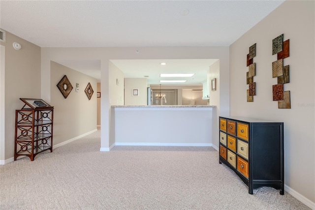 interior space with kitchen peninsula, light carpet, and a notable chandelier