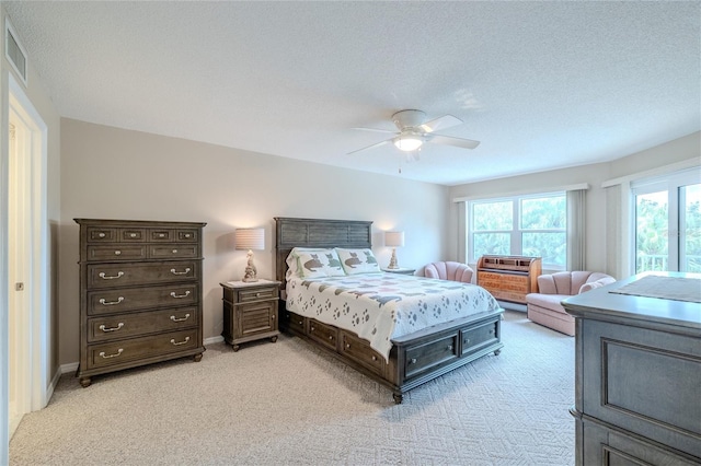 bedroom with ceiling fan, light carpet, and a textured ceiling