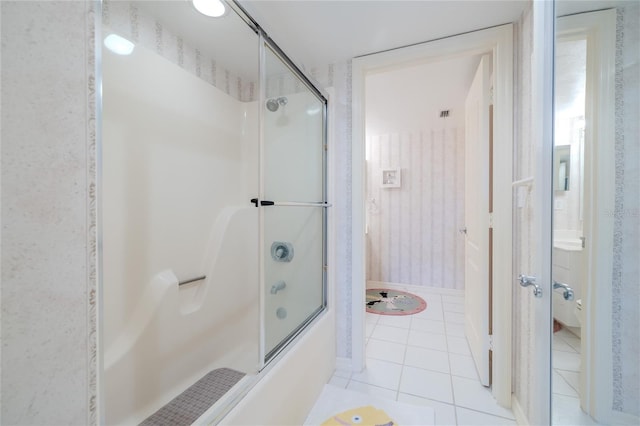 bathroom featuring tile patterned flooring and shower / bath combination with glass door