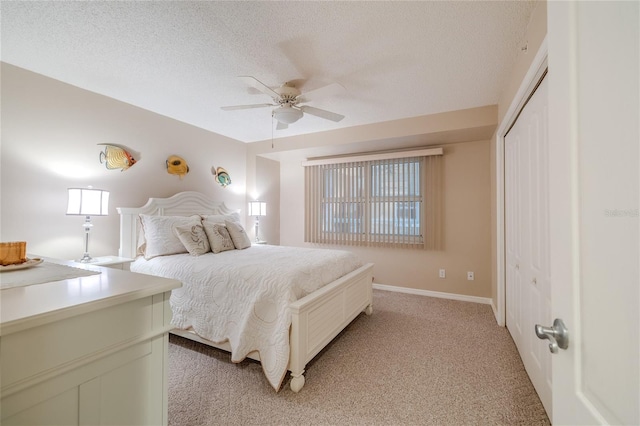 bedroom with a textured ceiling, light colored carpet, a closet, and ceiling fan