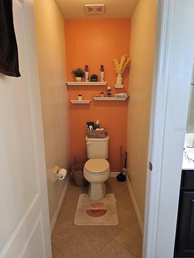 bathroom with tile patterned floors, vanity, a textured ceiling, and toilet