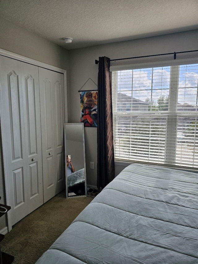 carpeted bedroom featuring a textured ceiling and a closet