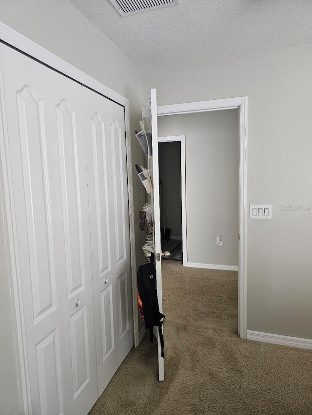 hall featuring carpet floors and a textured ceiling