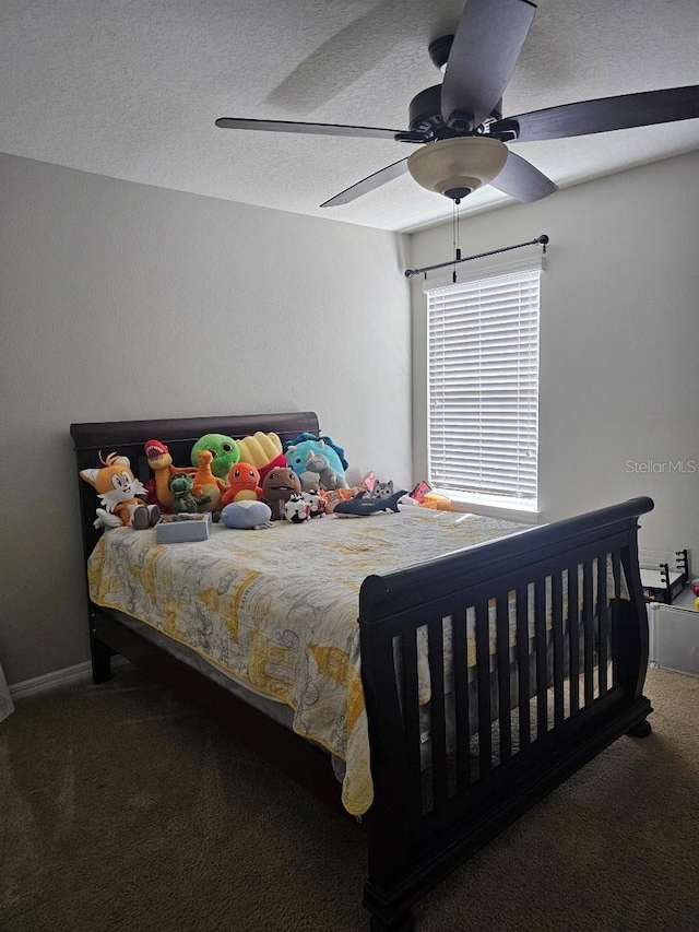 bedroom featuring dark colored carpet, a textured ceiling, and ceiling fan