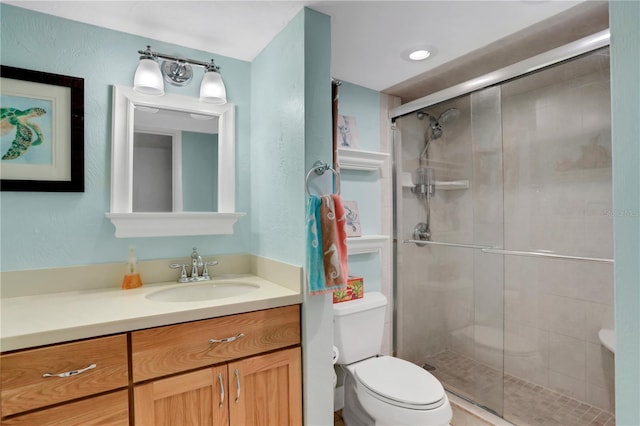 bathroom with vanity, a shower with shower door, and toilet