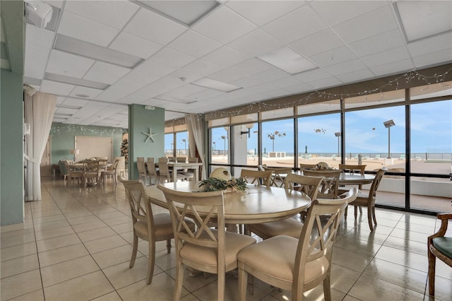 dining space with a drop ceiling and light tile patterned floors