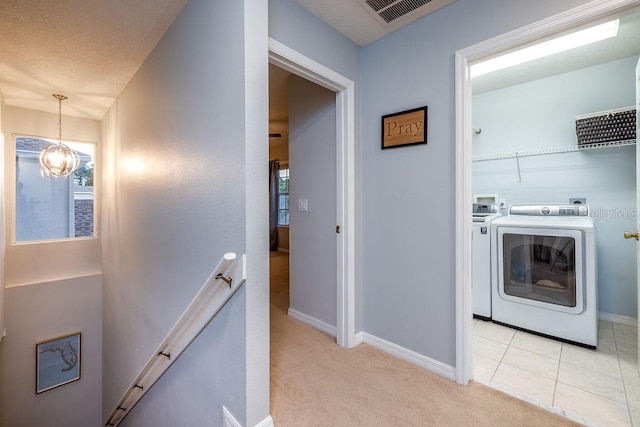 laundry area with a chandelier, a healthy amount of sunlight, washer and clothes dryer, and light colored carpet