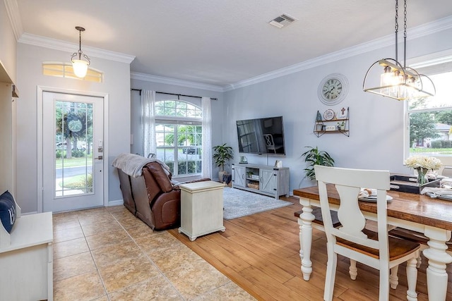 living room featuring an inviting chandelier, ornamental molding, and light wood-type flooring